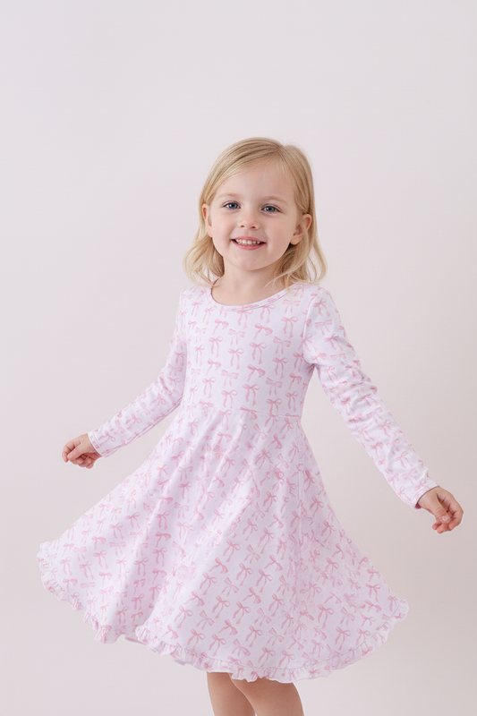 Young girl wearing a pink dress with a subtle pattern on a white background